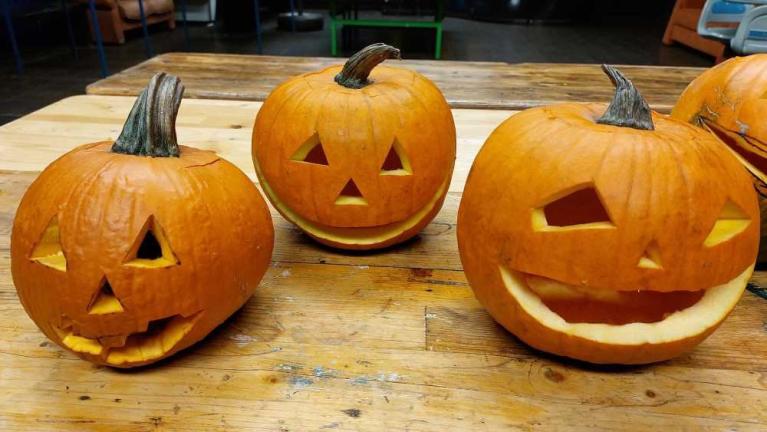 Drei geschnitzte Halloween-Kürbisse auf einem Holztisch