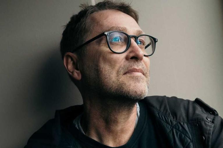 Porträt eines Mannes mit Brille, der seitlich in die Ferne blickt