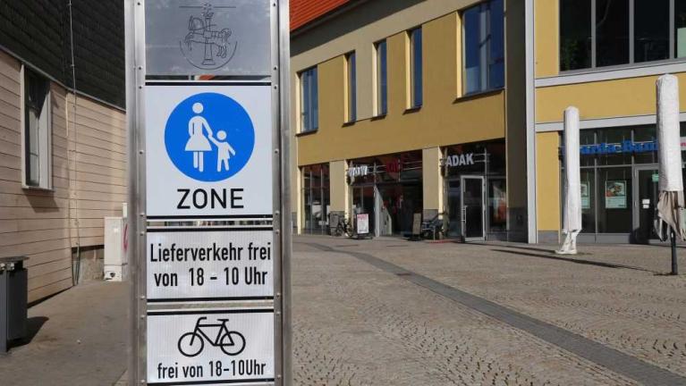 Straßenschild mit Fußgängerzone und Lieferverkehr-Hinweis vor Gebäuden