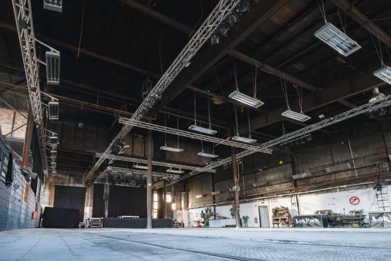 Leere Industriehalle mit hoher Decke, Bühnenbeleuchtung und abgesperrter Bühne