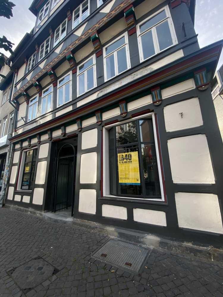 Fachwerkhaus mit mehreren Fenstern und Eingang an einer gepflasterten Straße