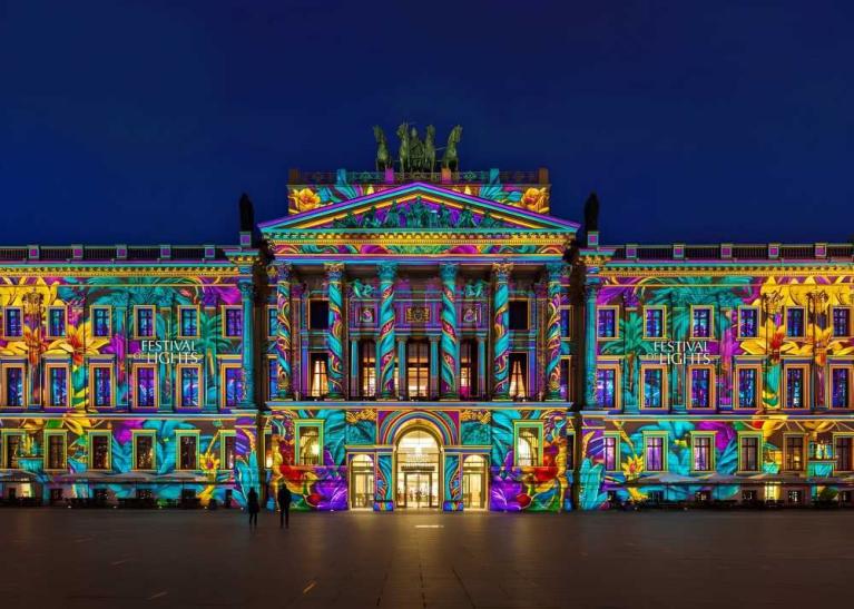 Ein historisches Gebäude wird bei Nacht mit bunten Festival-Lights angestrahlt
