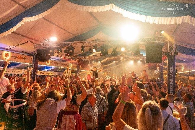 Menschenmenge feiert in einem Festzelt bei Konzert mit Bühnenlicht