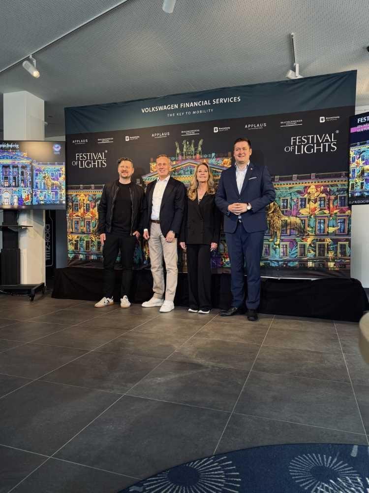 Vier Personen stehen vor einer Festival-of-Lights-Wand mit Volkswagen-Financial-Services-Banner