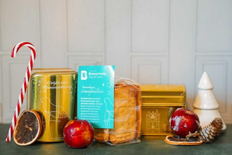 Weihnachtliche Geschenkverpackung mit Gebäck, Äpfeln, Zuckerstange und Dekoration