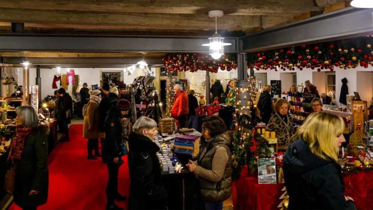 Menschen besuchen einen festlich geschmückten Indoor-Markt mit Verkaufsständen