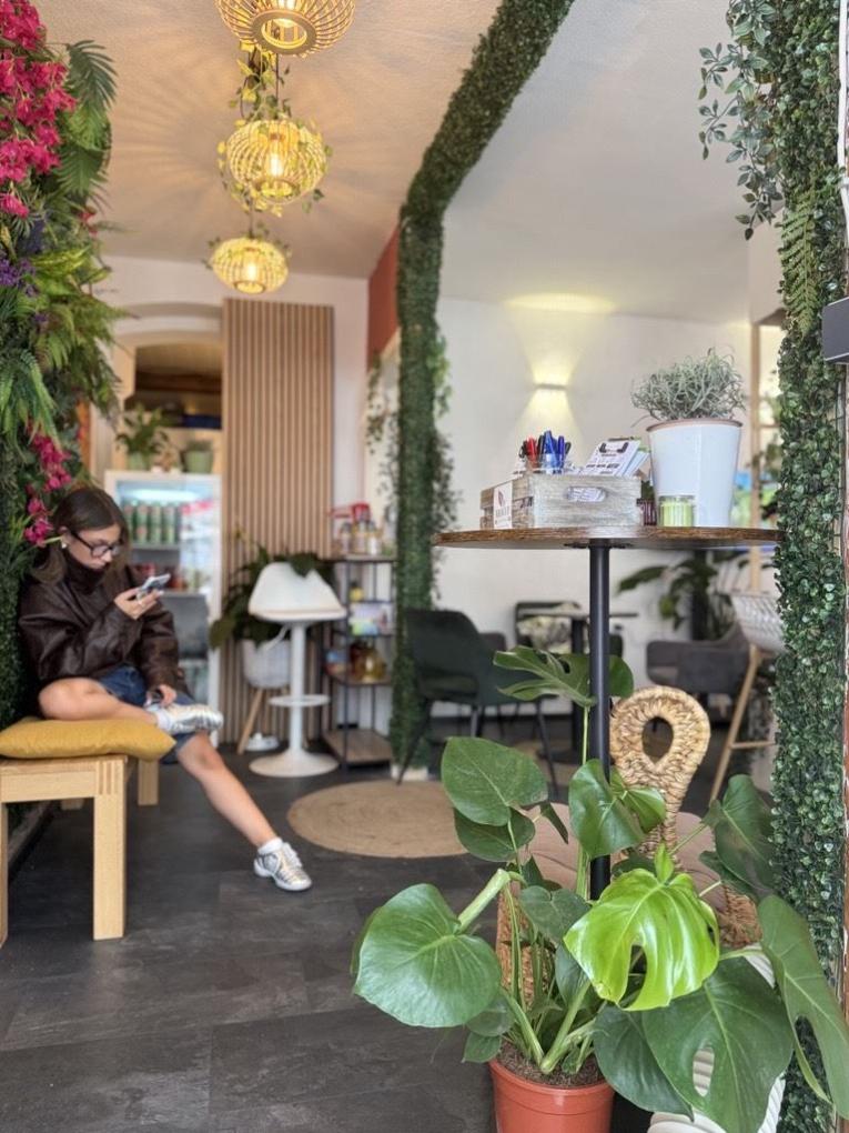 Innenraum eines grün dekorierten Cafés mit einer sitzenden Frau am linken Rand