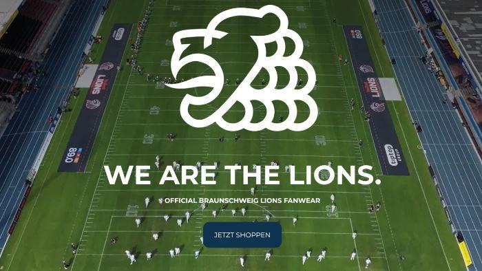 Luftaufnahme eines Footballfeldes mit großem Löwenlogo und dem Schriftzug We are the Lions