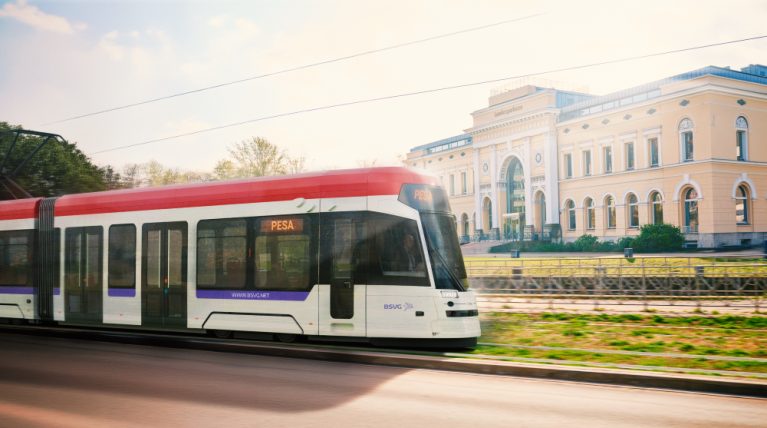 Ein moderner Straßenbahnzug fährt vor einem historischen Gebäude entlang